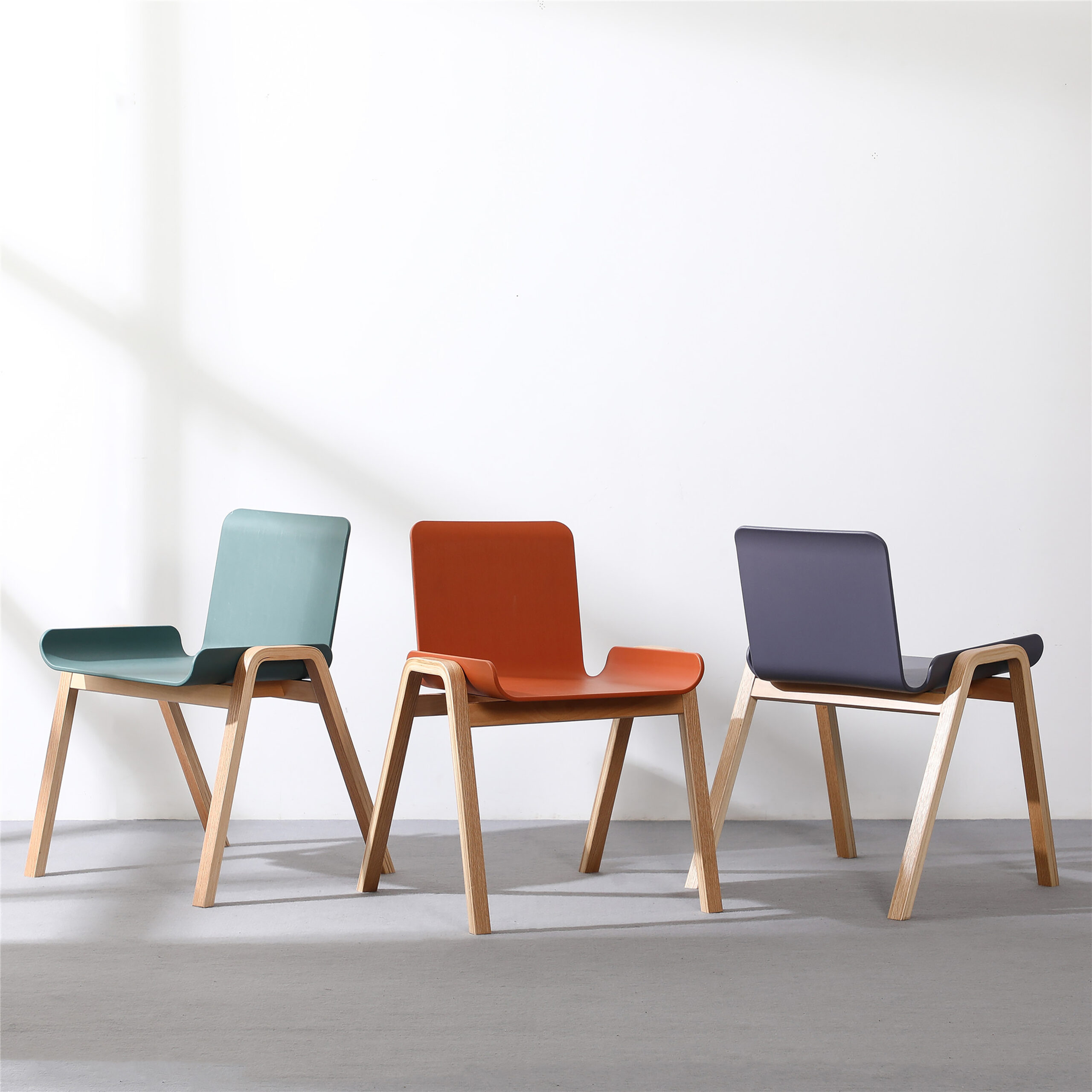 3 identical chairs sit around each other in different colors